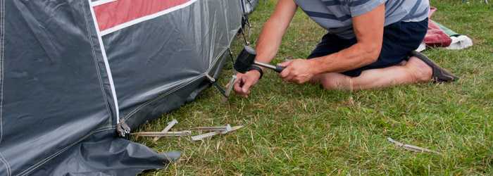 man putting in tent pegs with mallet